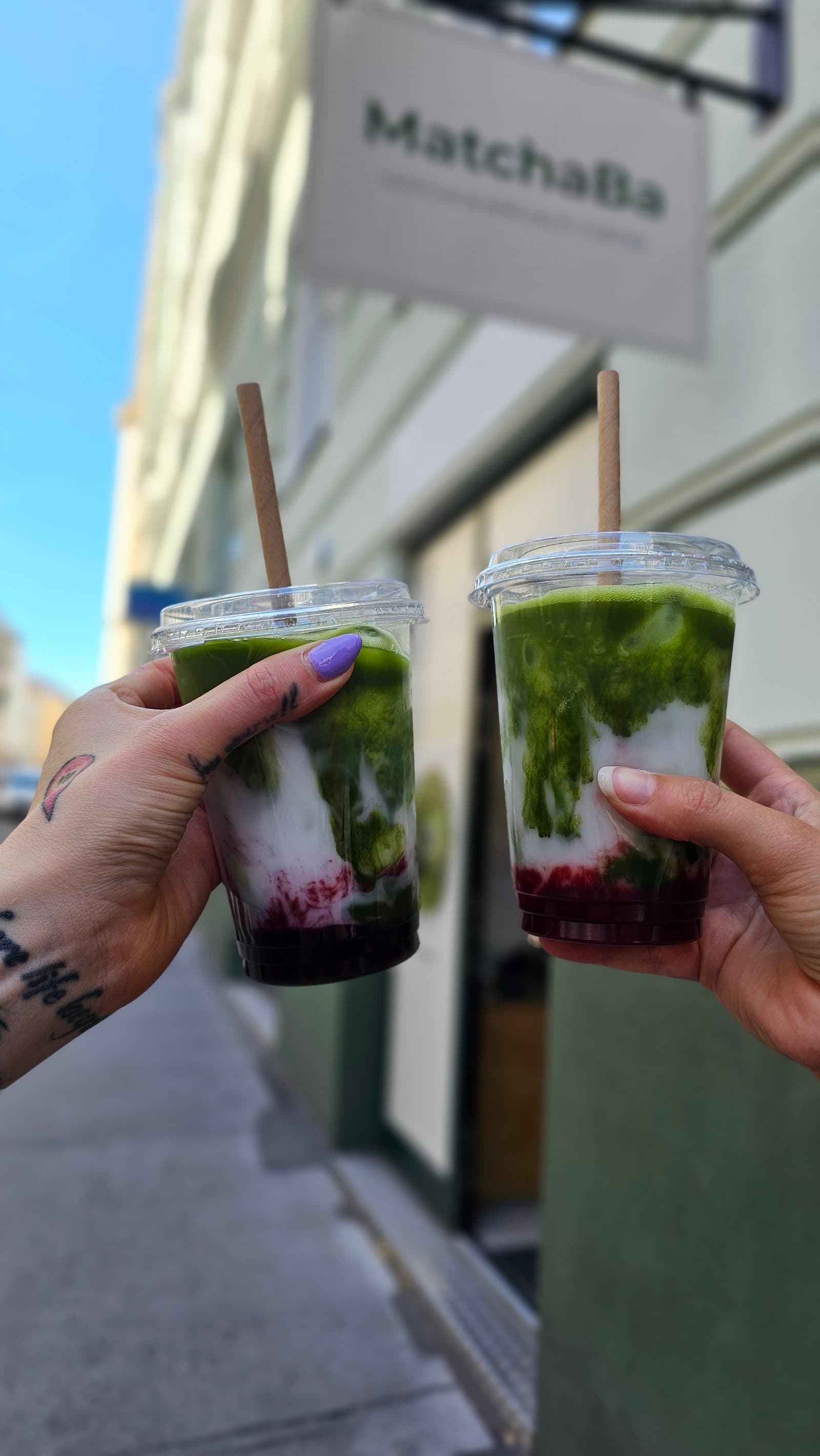Zwei Iced Matcha Drinks vor dem MatchaBa Schild in Wien